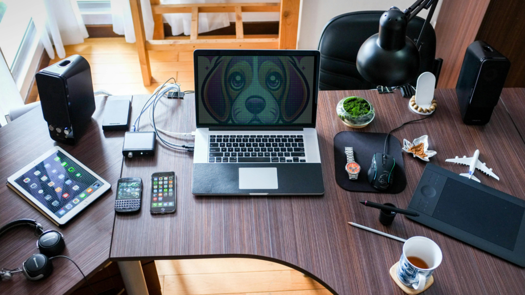 a desk covered in various devices with a laptop screen showing the Purple Beagle Digital Logo visible through green binary code